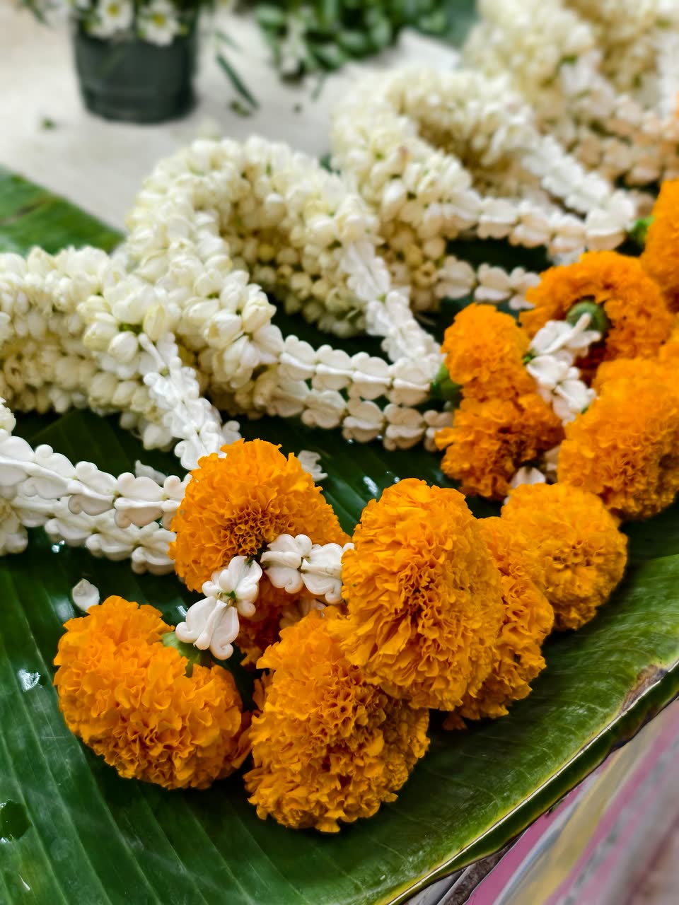 Jasmine and marigold strings laid on a banana leaf